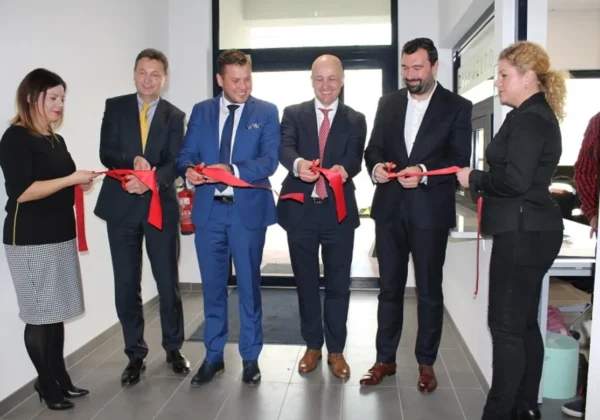 Grupa siedmiu osób w formalnych ubraniach przecina czerwone wstęgi podczas ceremonii otwarcia obiektu REMONDIS.