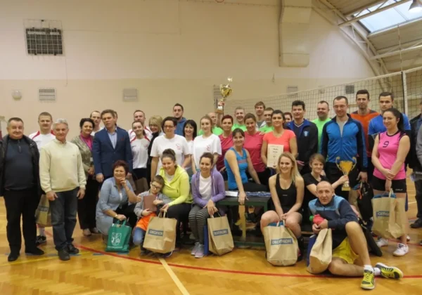 Grupa uczestników VI Powiatowego Turnieju Piłki Siatkowej Pracowników Oświaty ZNP w Płocku stoi razem w hali sportowej z pucharami i nagrodami.