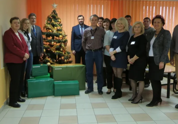 Grupa pracowników starostwa stoi w holu przy choince, obok zapakowanych prezentów przygotowanych na Szlachetną Paczkę.