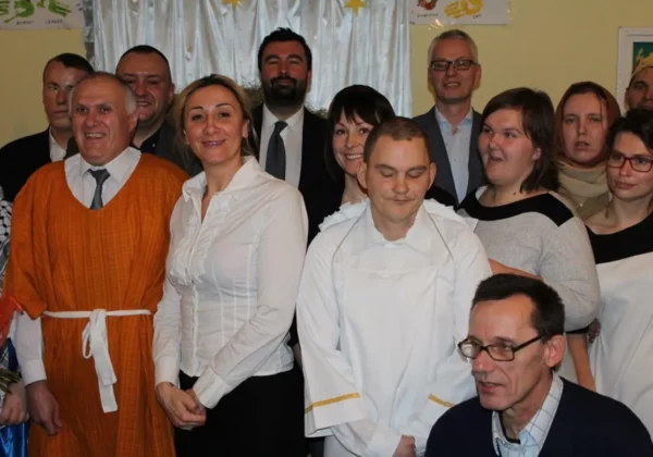 Grupa osób podczas Wigilii w Warsztacie Terapii Zajęciowej w Męczeninie, stojąca i uśmiechnięta do aparatu.
