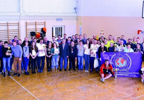 Duża grupa uczestników i organizatorów VII Mazowieckiego Halowego Turnieju Piłki Siatkowej Drużyn Mieszanych o Puchar Starosty Płockiego stoi na boisku, prezentując trofea i medale.