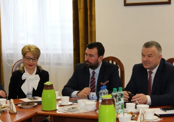 Trzech urzędników w garniturach siedzi przy stole podczas formalnego spotkania, omawiając powrót posterunku w Staroźrebach.