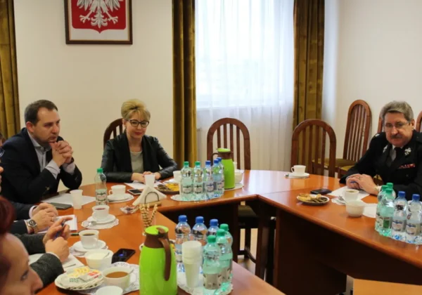 Grupa urzędników i funkcjonariuszy siedzi przy stole w sali konferencyjnej podczas posiedzenia Komisji Bezpieczeństwa i Porządku.