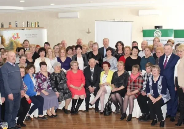 Duża grupa uczestników, głównie dorosłych, stoi i siedzi w sali konferencyjnej podczas I Powiatowego Spotkania z Sołtysami.