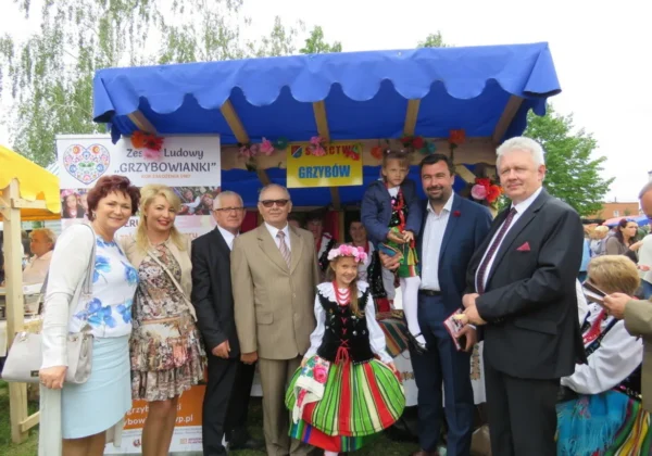 Grupa ludzi, w tym osoby w strojach ludowych, stoi przed kolorowym pawilonem z dekoracjami podczas inauguracji Roku Rzeki Wisły na Dniu Ziemi w Słubicach.