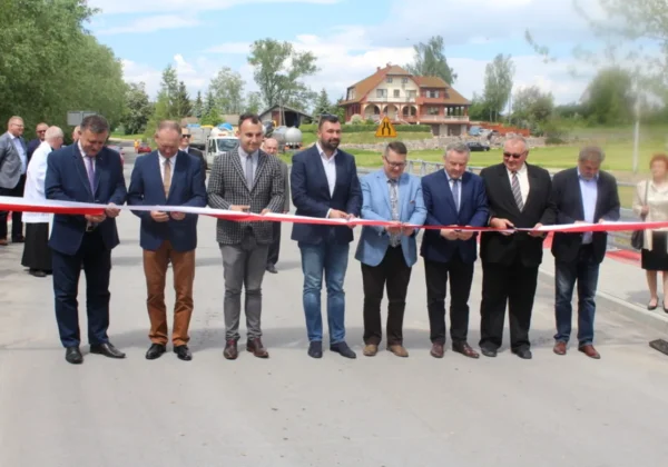 Grupa mężczyzn w garniturach przecina czerwono-białą wstęgę podczas uroczystego otwarcia nowej inwestycji drogowej w gminie Stara Biała.