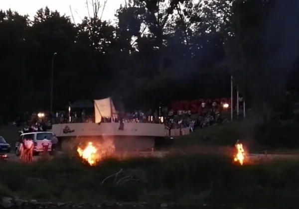 Wieczorne XXXVIII Dni Wisły w Wyszogrodzie: tłum ludzi zgromadzony na widowni przy scenie obserwuje pokaz, a na trawie w pobliżu płoną dwa ogniska.