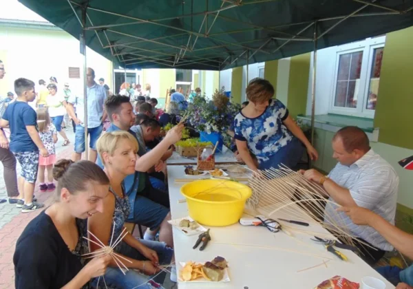 Uczestnicy XXIV Dnia Humoru i Satyry w Domu Pomocy Społecznej w Zakrzewie pod namiotem tworzą dekoracje z patyków i gałązek podczas warsztatów.