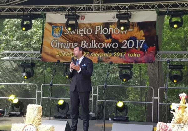 Mężczyzna w garniturze przemawia do mikrofonu na scenie podczas Święta Plonów Gmina Bulkowo 2017.