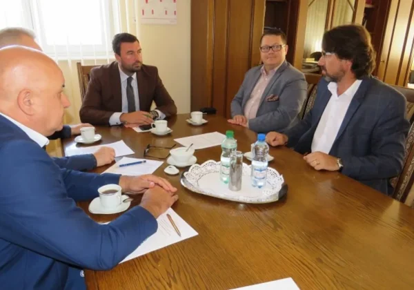 Grupa pięciu mężczyzn w garniturach siedzi przy stole podczas spotkania o nowych inwestycjach drogowych w gminie Drobin.