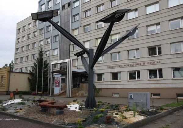 Czarna nowoczesna rzeźba o trzech rozchodzących się ramionach stoi w ogrodzie przy wejściu do Starostwa Powiatowego w Płocku.