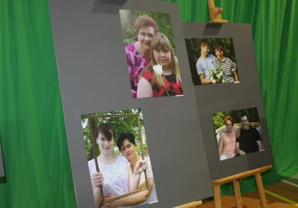 Dwie szare tablice wystawowe z fotografiami rodzin, ustawione na tle zielonej kurtyny podczas Dnia Edukacji Narodowej w Specjalnym Ośrodku Szkolno-Wychowawczym w Płocku.