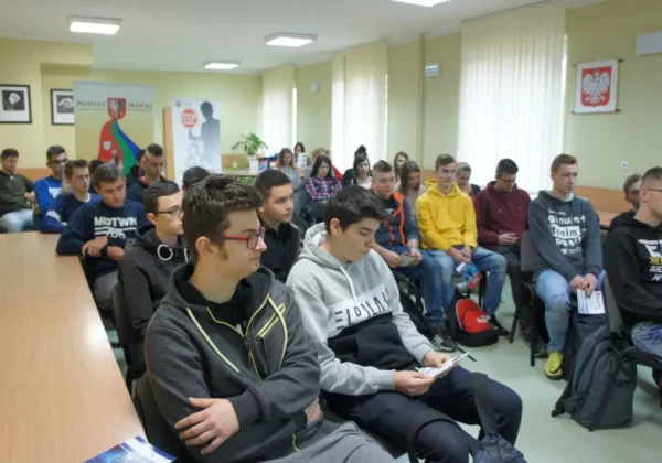Grupa młodzieży siedzi w sali konferencyjnej podczas spotkania edukacyjnego o narkotykach i dopalaczach – przyczyny przemocy i destabilizacji rodziny.