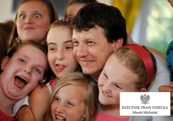 Dorosły mężczyzna otacza radosne, uśmiechnięte dzieci podczas wspólnego zdjęcia z okazji nadejścia Nowego Roku.