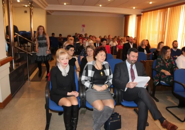 Uczestnicy siedzą w sali konferencyjnej podczas podsumowania konkursu „Działaj Lokalnie”; na pierwszym planie widoczne trzy osoby w eleganckich strojach.