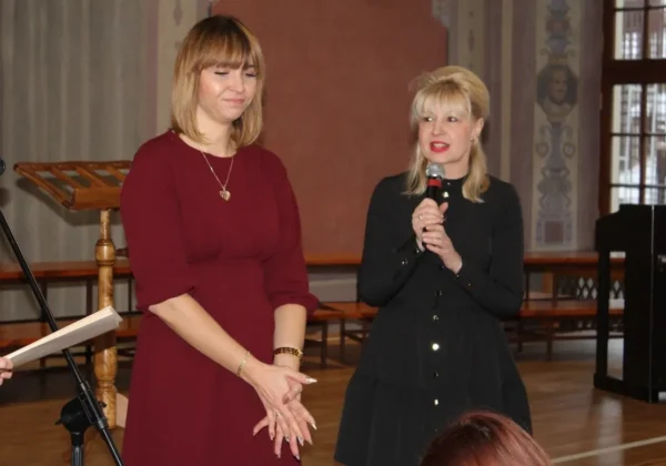 Na scenie w sali widowiskowej stoją dwie kobiety podczas finału tegorocznej Akcji Gwiazdka; jedna mówi do mikrofonu, druga ma ręce złożone.