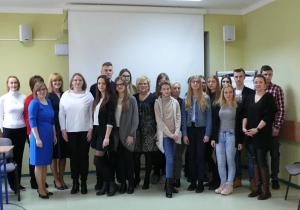 Grupa uczniów i nauczycieli stoi razem w sali szkolnej przed ekranem projekcyjnym podczas VIII Powiatowego Konkursu Wiedzy o Francji, Niemczech, Rosji i Wielkiej Brytanii.