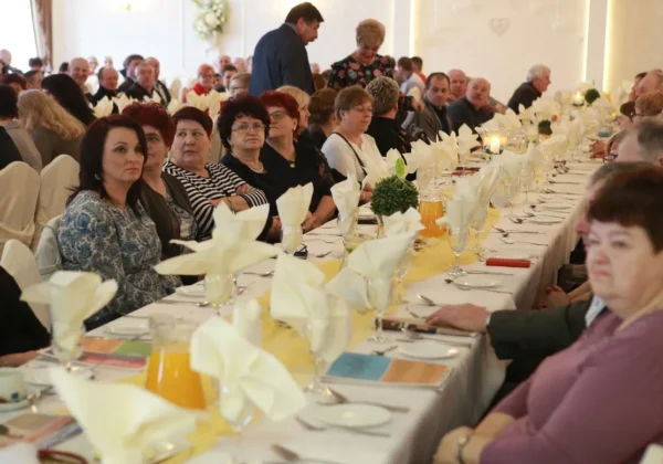 Duża grupa mieszkańców siedzi przy długim, elegancko zastawionym stole w sali bankietowej podczas II Powiatowego Dnia Sołtysa.