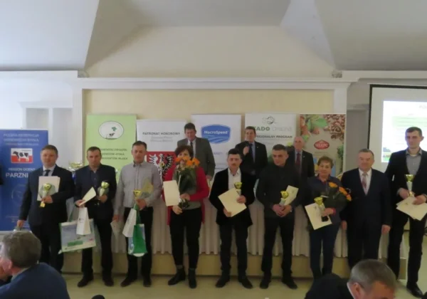 Grupa osób na scenie podczas wręczania nagród i dyplomów na Spotkaniu Hodowców Bydła w Brochocinie, w tle banery sponsorów.