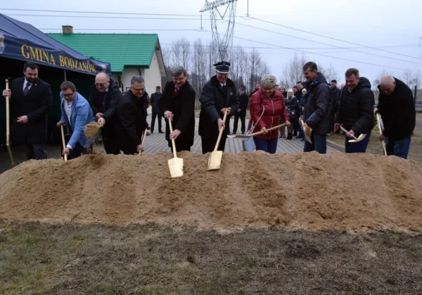 Symboliczna ceremonia rozpoczęcia budowy oczyszczalni ścieków w Bodzanowie: grupa osób kopie ziemię łopatami przed namiotem z napisem „Gmina Bodzanów”.