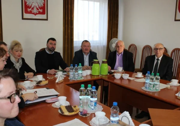 Grupa osób siedzi przy dużym stole w sali konferencyjnej, omawiając bezpieczeństwo pożarowe mieszkańców powiatu płockiego.
