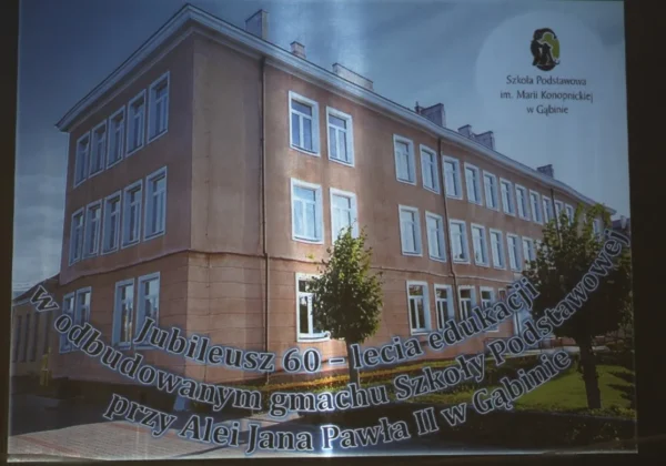 Widok na gmach Szkoły Podstawowej im. Marii Konopnickiej w Gąbinie z banerem upamiętniającym jubileusz 60-lecia edukacji w gminie, przy Aleji Jana Pawła II.