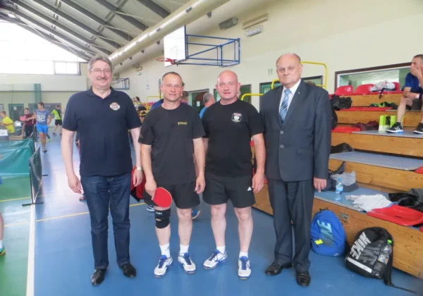 Czterech mężczyzn stoi obok siebie na hali sportowej podczas Rekordowego Turnieju Tenisa Stołowego w Łącku.
