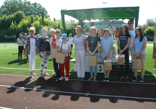 Grupa uczestników i organizatorów stoi na bieżni stadionu podczas VIII Powiatowej Olimpiady Integracyjnej pod hasłem „SPORT dla NIEPODLEGŁEJ”.