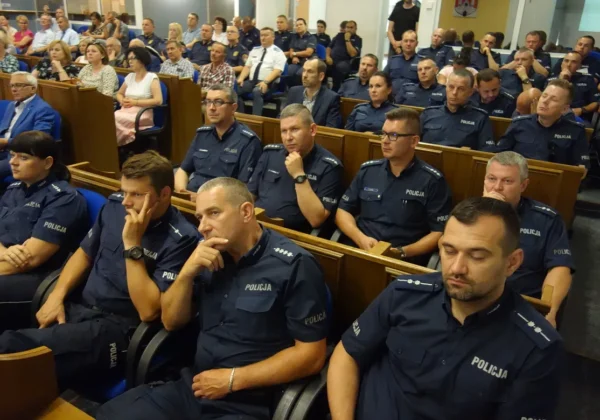 W sali konferencyjnej odbywa się debata pt. „Porozmawiajmy o bezpieczeństwie, możesz mieć na nie wpływ”; w pierwszym planie widoczni są policjanci w mundurach.