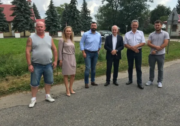 Grupa sześciu osób stoi na poboczu drogi podczas spotkania dotyczącego przebudowy drogi powiatowej Bulkowo-Kobylniki.