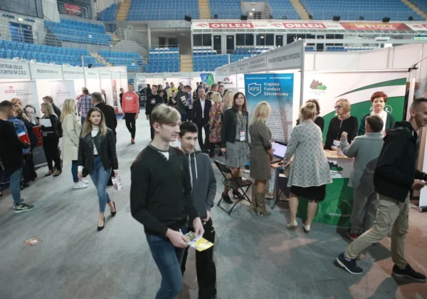 Tłum uczestników i wystawców odwiedzających liczne stoiska podczas Płockich Targów Aktywności Zawodowej w hali sportowej.