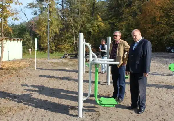 Na zdjęciu widać mężczyzn oglądających sprzęt do ćwiczeń w nowo powstającym miejscu wypoczynku nad Jeziorem Łąckim Dużym.