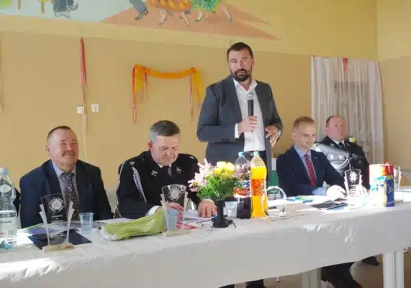 Na zdjęciu przedstawiono uczestników spotkania w OSP Juryszewo, w tym mężczyzn wygłaszających przemówienia oraz dekoracje przy stole, w atmosferze gratulacji dla druhów.