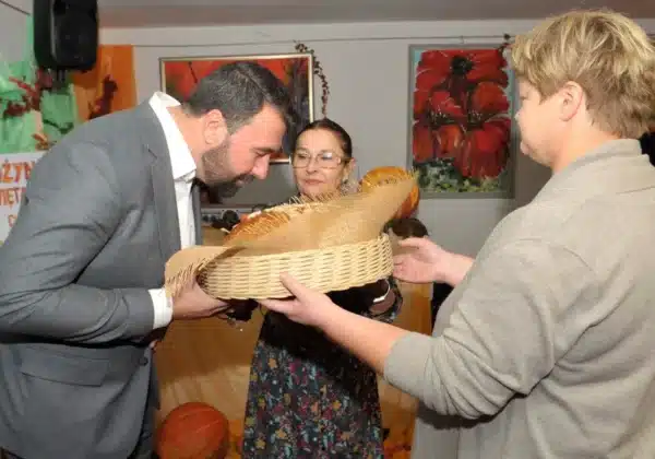 W trakcie dożynek w Domu Pomocy Społecznej „Nad Jarem” w Nowym Miszewie, mężczyzna przyjmuje od dwóch kobiet kosz z darami.
