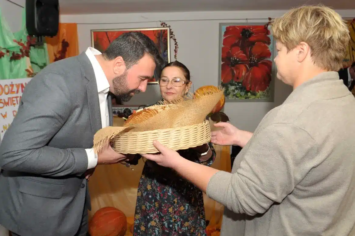 W trakcie dożynek w Domu Pomocy Społecznej „Nad Jarem” w Nowym Miszewie, mężczyzna przyjmuje od dwóch kobiet kosz z darami.