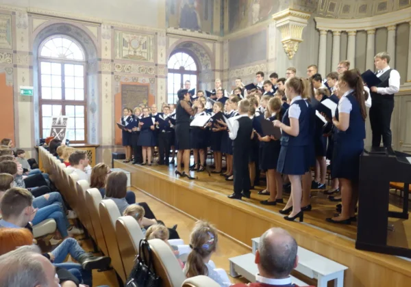 Chór szkolny w granatowych mundurkach wykonuje występ na scenie w sali koncertowej podczas czwartej edycji Akcji Gwiazdka.