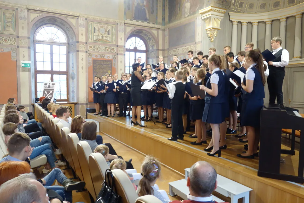 Chór szkolny w granatowych mundurkach wykonuje występ na scenie w sali koncertowej podczas czwartej edycji Akcji Gwiazdka.