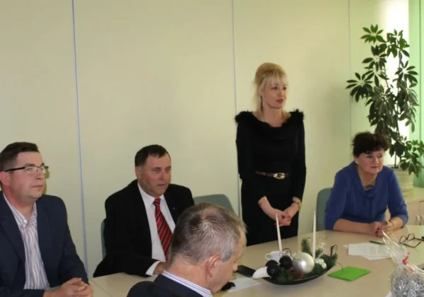 Uczestnicy spotkania wigilijnego Powiatowej Rady Rynku Pracy siedzą przy stole w jasnym biurowym pomieszczeniu, a na stole widoczne są świąteczne dekoracje.