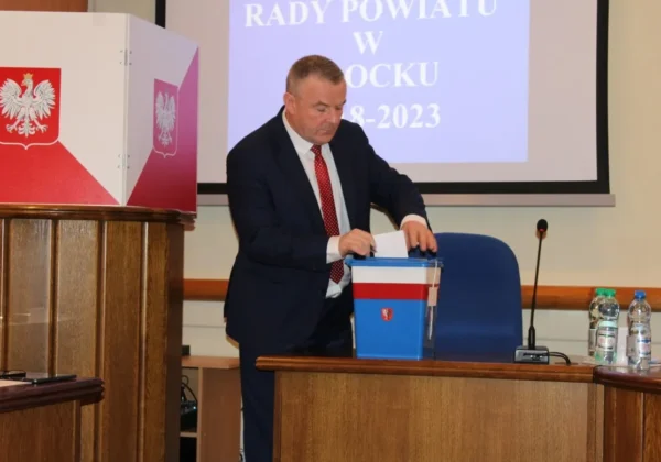 Osoba w garniturze wrzuca kartę do urny podczas II sesji Rady Powiatu w Płocku.