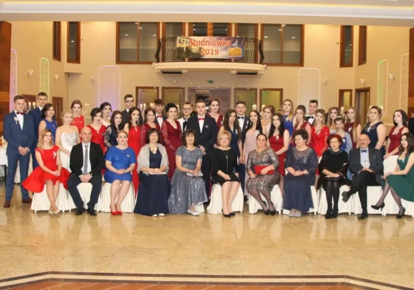 Grupa uczniów i nauczycieli Zespołu Szkół im. St. Staszica w Gąbinie podczas Studniówki 2019, ustawiona w sali balowej przed banerem „Studniówka 2019”.