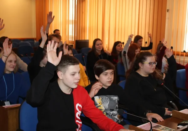 Uczniowie Ogólnokształcącej Szkoły Muzycznej podczas wizyty w Starostwie siedzą w sali konferencyjnej; część z nich podnosi ręce, a przed nimi znajdują się mikrofony.