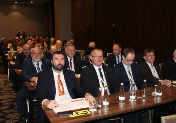 Uczestnicy XXIV Zgromadzenia Ogólnego Związku Powiatów Polskich siedzą przy stołach w sali konferencyjnej, ubrani w garnitury, z dokumentami i butelkami wody.