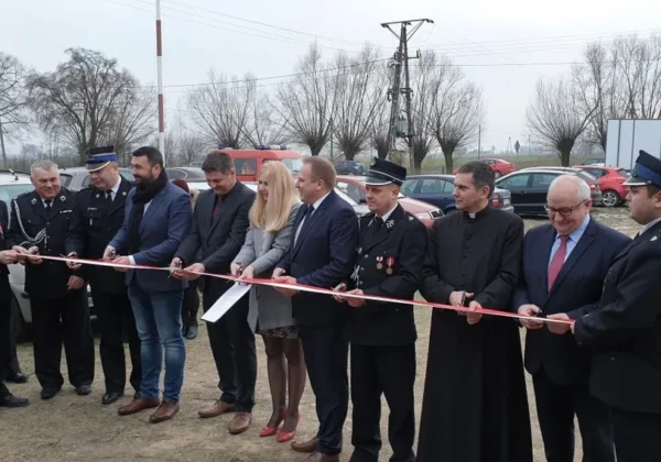 Grupa osób, w tym strażacy w mundurach i urzędnicy, przecina wstęgę podczas uroczystego otwarcia remizy strażackiej w Worowicach.