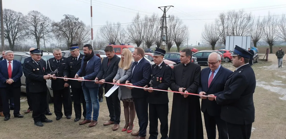 Grupa osób, w tym strażacy w mundurach i urzędnicy, przecina wstęgę podczas uroczystego otwarcia remizy strażackiej w Worowicach.