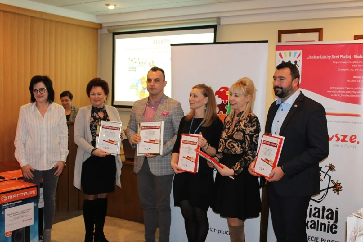 Szóstka osób stojących w sali konferencyjnej powiatu płockiego trzyma certyfikaty podczas inauguracji kolejnej edycji konkursu grantowego „Działaj Lokalnie”.