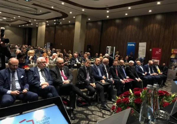 Uczestnicy w garniturach siedzą w pierwszym rzędzie podczas XXV Zgromadzenia Ogólnego Związku Powiatów Polskich w sali konferencyjnej.