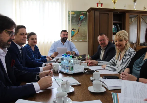 Grupa pracowników i urzędników siedzi przy stole w biurze Powiatowego Urzędu Pracy, omawiając dokumenty podczas spotkania podsumowującego ubiegły rok.