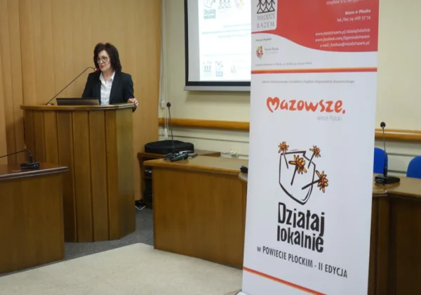 Prelegentka stoi za mównicą podczas warsztatów ws. RODO dla NGO, w sali konferencyjnej z banerami „Działaj Lokalnie” i „Mazowsze”.
