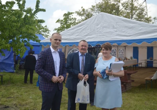 Trzy osoby stoją przed namiotem podczas obchodów 45-lecia Rodzinnego Ogrodu Działkowego Drogowiec w Stróżewku.