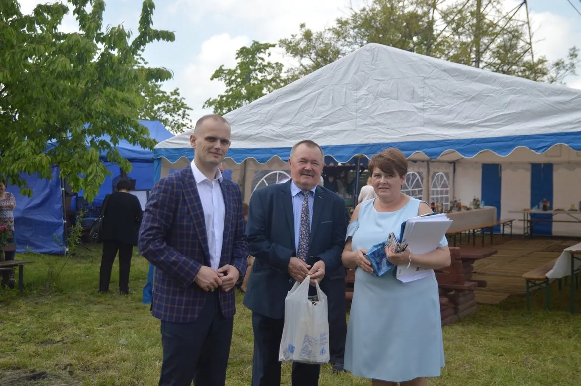 Trzy osoby stoją przed namiotem podczas obchodów 45-lecia Rodzinnego Ogrodu Działkowego Drogowiec w Stróżewku.